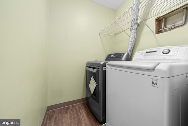 laundry area featuring laundry area, baseboards, dark wood finished floors, and washing machine and clothes dryer