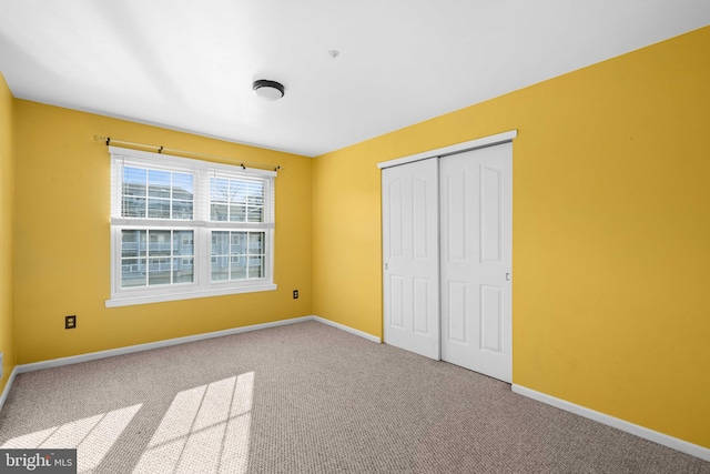 unfurnished bedroom with carpet, a closet, and baseboards