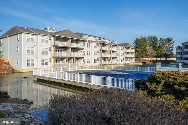 view of building exterior with a water view and fence