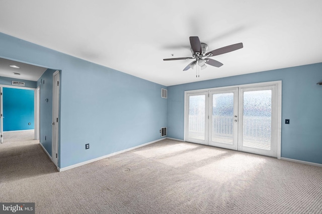 carpeted spare room featuring visible vents, baseboards, and a ceiling fan