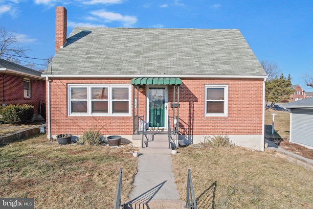 bungalow-style home with brick siding, a chimney, and a front yard