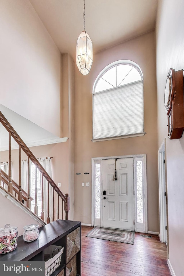 entrance foyer featuring stairway, baseboards, a towering ceiling, and wood finished floors