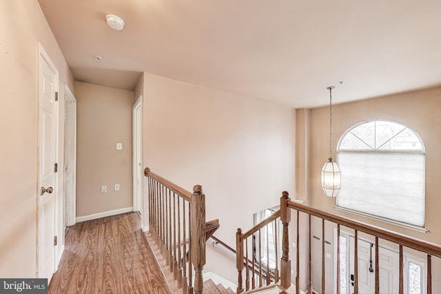 hall with baseboards, an upstairs landing, and wood finished floors