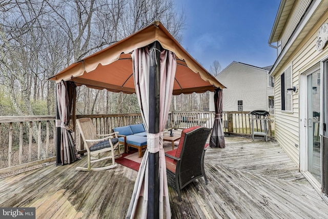 wooden terrace featuring a gazebo and an outdoor living space