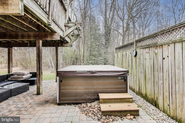 view of patio / terrace featuring fence and a hot tub