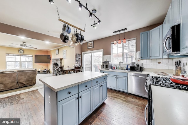 kitchen with decorative backsplash, hardwood / wood-style flooring, appliances with stainless steel finishes, and a kitchen island
