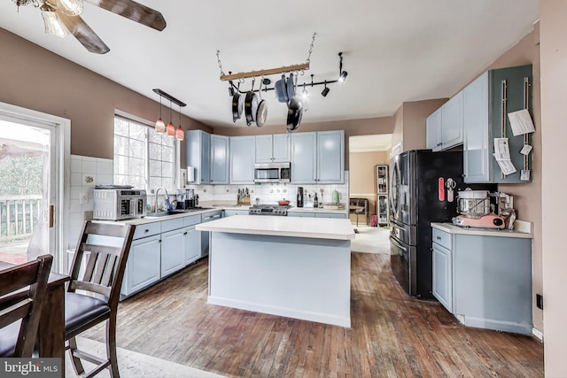 kitchen featuring tasteful backsplash, stainless steel microwave, light countertops, and a sink