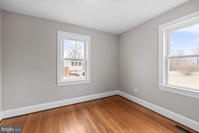 empty room featuring visible vents, baseboards, and wood finished floors