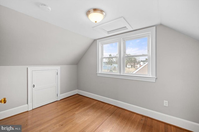 additional living space with lofted ceiling, light wood-type flooring, and baseboards