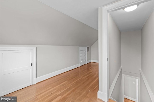 additional living space with lofted ceiling, visible vents, light wood-style flooring, and baseboards