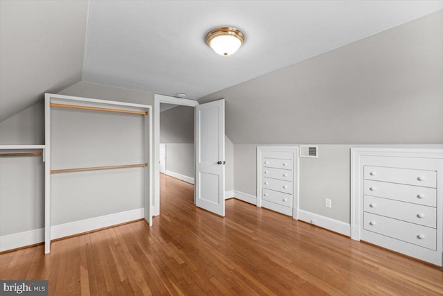 bonus room with lofted ceiling, wood finished floors, visible vents, and baseboards