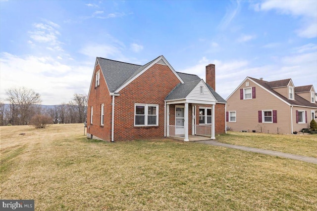 view of front of house featuring brick siding, roof with shingles, a chimney, a porch, and a front lawn