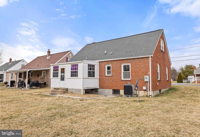 rear view of property with entry steps, brick siding, a lawn, and cooling unit