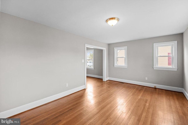 spare room featuring baseboards and light wood-style floors