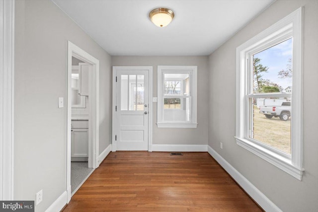 doorway to outside featuring visible vents, baseboards, and wood finished floors