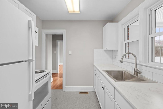 kitchen featuring white appliances, a sink, white cabinets, tasteful backsplash, and plenty of natural light