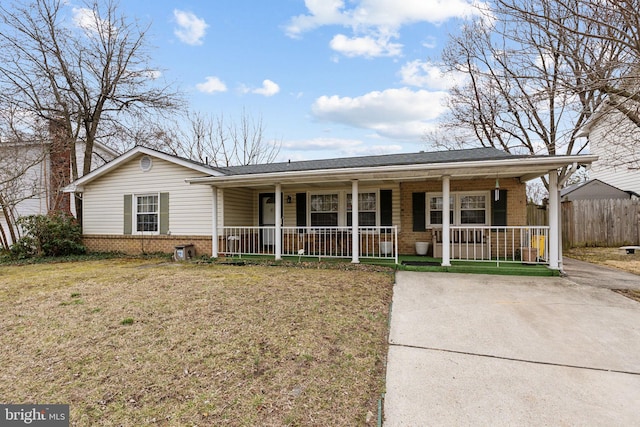 ranch-style home with covered porch, a shingled roof, a front yard, and brick siding