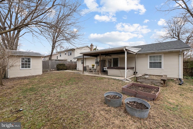 back of property with a hot tub, a garden, a fenced backyard, an outdoor structure, and a patio area