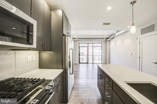 kitchen with stainless steel appliances, light countertops, visible vents, and tasteful backsplash