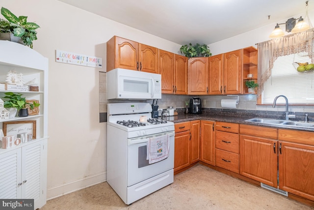 kitchen featuring brown cabinets, visible vents, decorative backsplash, a sink, and white appliances