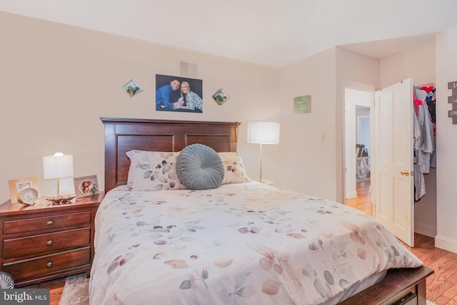 bedroom featuring light wood-style floors, visible vents, and baseboards