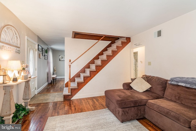 living area featuring stairs, wood-type flooring, visible vents, and baseboards