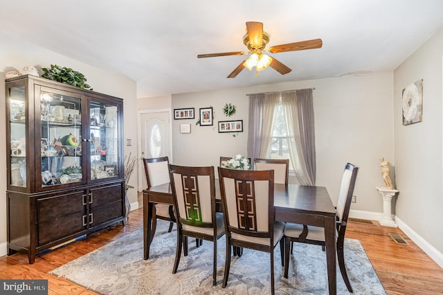 dining room with ceiling fan, wood finished floors, visible vents, and baseboards