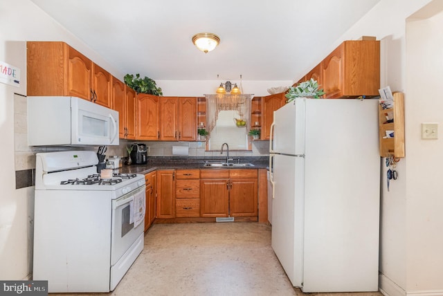 kitchen with white appliances, a sink, backsplash, brown cabinetry, and dark countertops