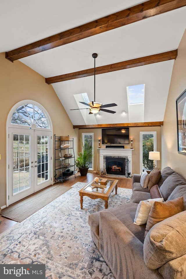 living room with vaulted ceiling with skylight, french doors, a fireplace, and wood finished floors