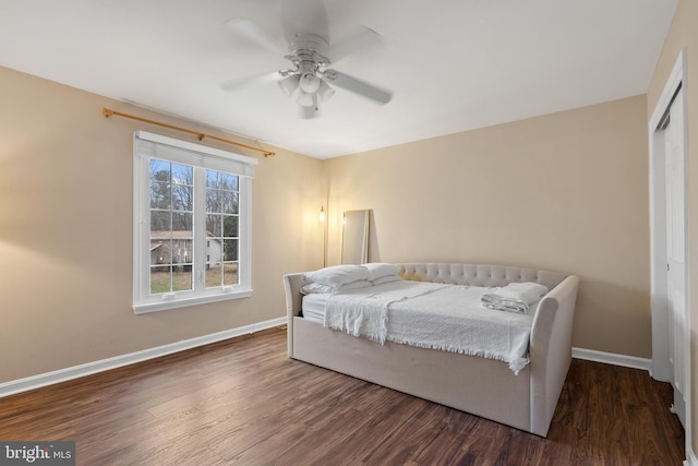 bedroom featuring ceiling fan, a closet, wood finished floors, and baseboards