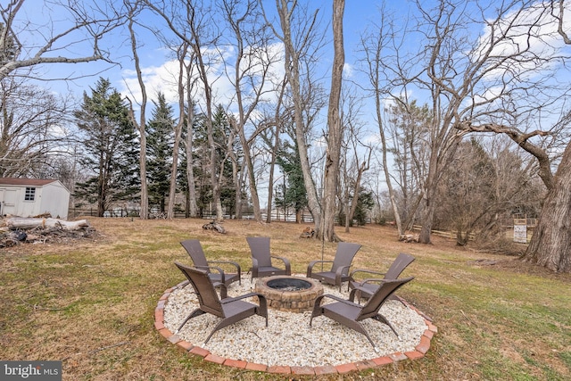 view of yard with an outbuilding, fence, a fire pit, and a shed