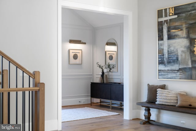 foyer featuring lofted ceiling, stairway, wood finished floors, and baseboards