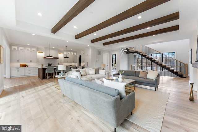 living area with light wood-type flooring, beam ceiling, stairway, and recessed lighting