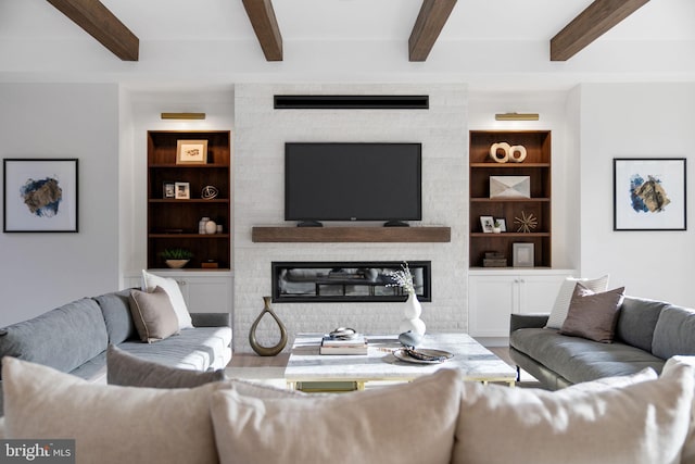 living room with built in features, a glass covered fireplace, beam ceiling, and wood finished floors