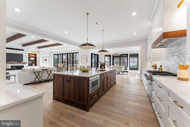 kitchen with wall chimney exhaust hood, dark brown cabinets, light wood-style flooring, and white cabinets