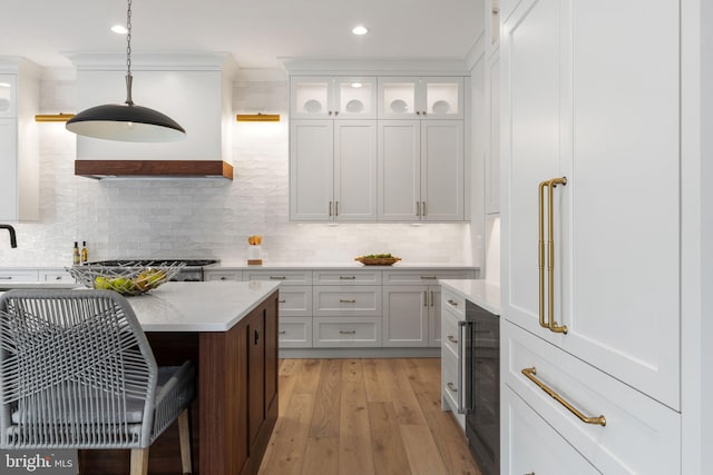 kitchen featuring beverage cooler, light wood-type flooring, white cabinetry, pendant lighting, and backsplash