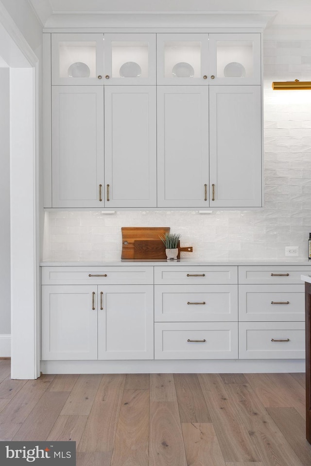 bar with light wood-type flooring and backsplash