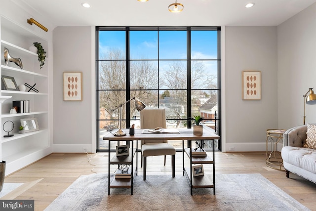 home office with light wood finished floors, baseboards, floor to ceiling windows, and recessed lighting