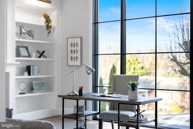 home office featuring built in shelves and wood finished floors