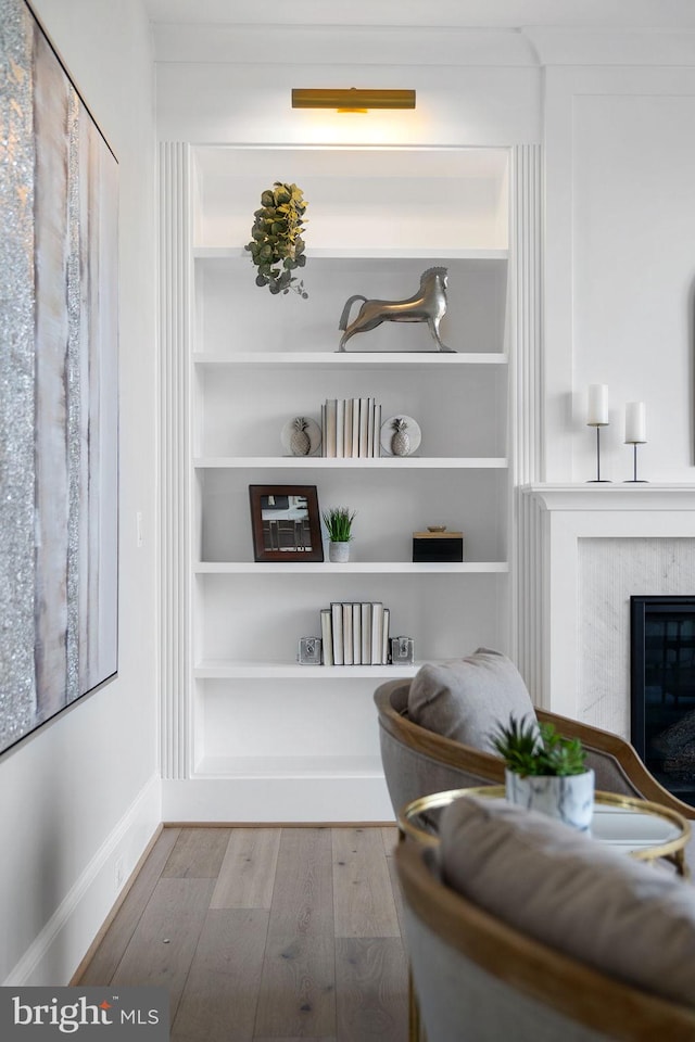 interior space with hardwood / wood-style floors, a glass covered fireplace, and built in features