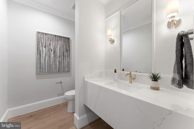 bathroom featuring baseboards, vanity, toilet, and wood finished floors