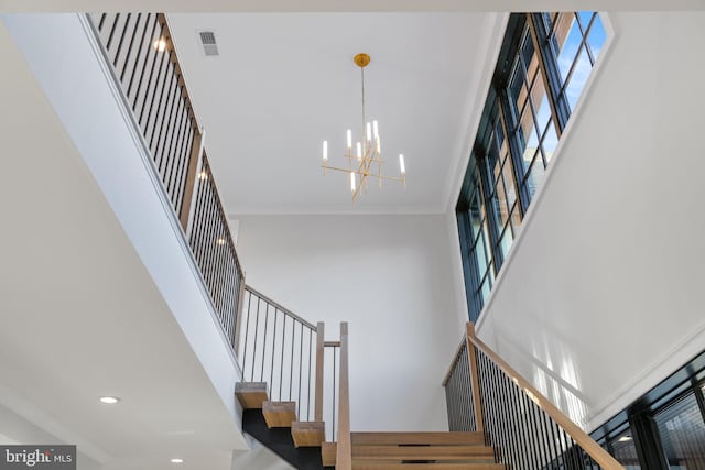 staircase featuring recessed lighting, a notable chandelier, a high ceiling, visible vents, and crown molding