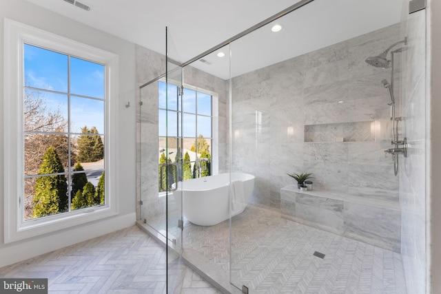 bathroom featuring recessed lighting, a freestanding bath, a wealth of natural light, and tiled shower