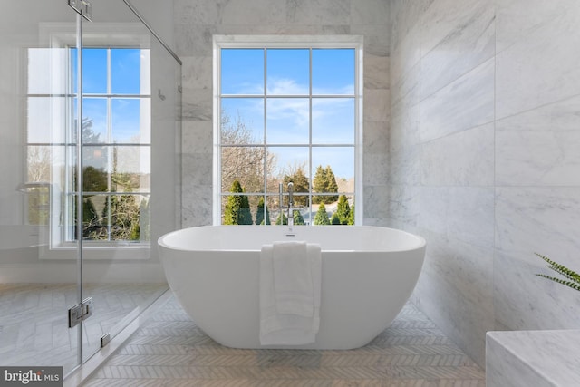 bathroom featuring a freestanding tub, tile patterned flooring, and tile walls