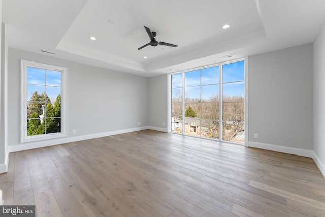 spare room with baseboards, a raised ceiling, wood finished floors, and recessed lighting