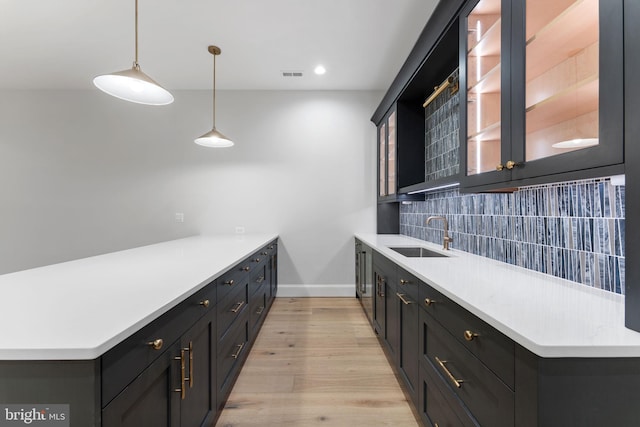 kitchen featuring light countertops, visible vents, decorative backsplash, a sink, and a peninsula