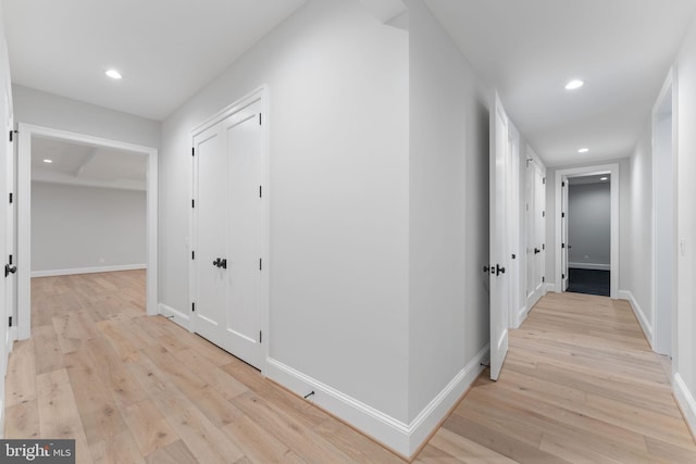 hall with light wood-style floors, recessed lighting, and baseboards