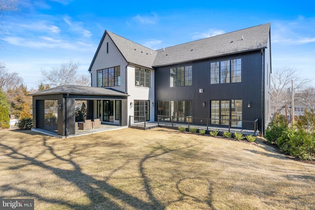 rear view of property featuring a yard, roof with shingles, and a patio area