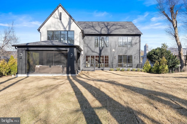 back of property with a yard, roof with shingles, a sunroom, and stucco siding