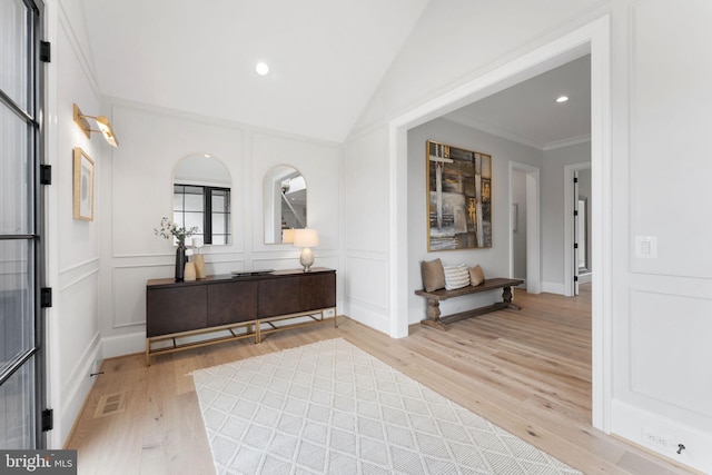 bathroom with wood finished floors, visible vents, and a decorative wall